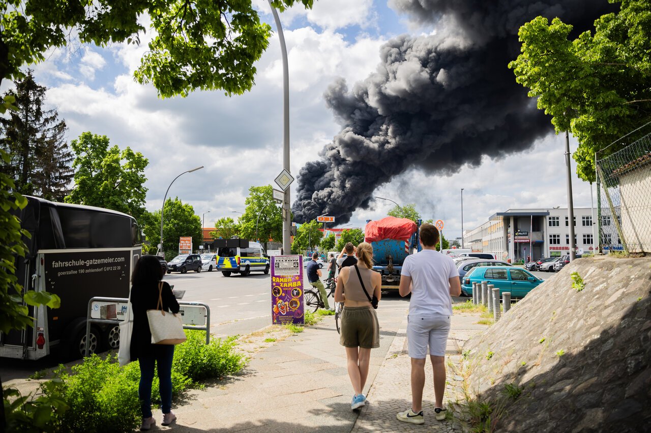 People walk in the area near the fire in Berlin on Friday. Residents have been urged to stay inside and keep their windows closed. 