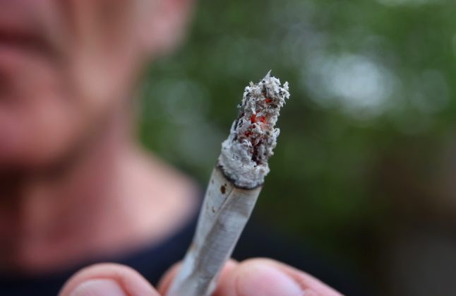 A man holds a lit joint in Germany