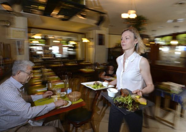 A server carries meals at a restaurant in France