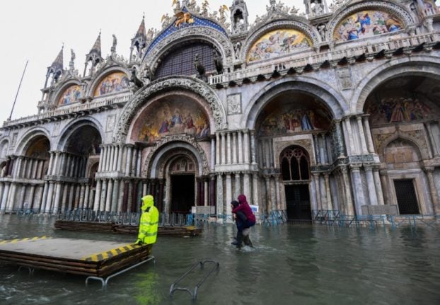 A municipal worker sets up a footbridge for pedestrians on a flooded St. Mark's Square