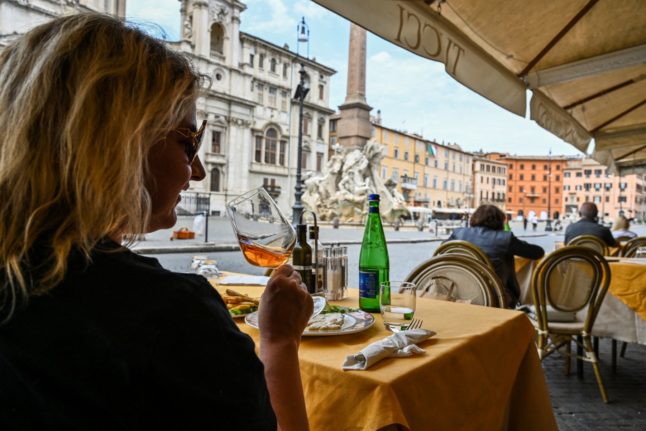 A woman has lunch at a restaurant in Piazza Navona, central Rome