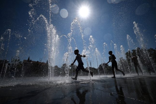 Children cool in a public fountain in Colmar.
