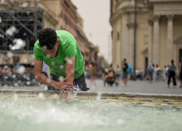 A man refreshes himself at a fountain in Rome in the middle of a heatwave.