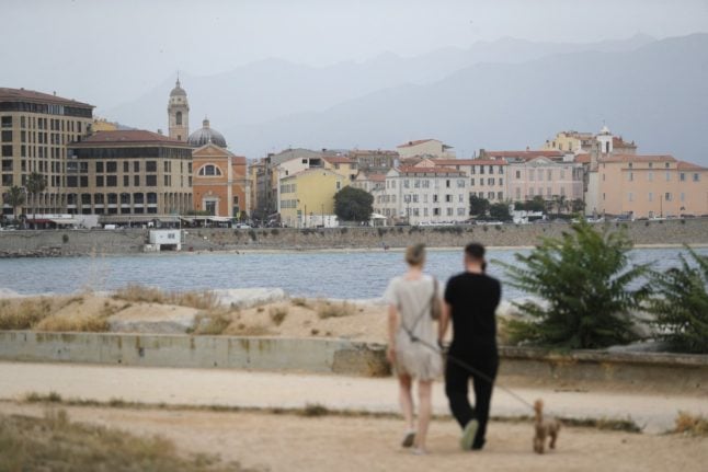 A couple walk along the seafront in Ajaccio, on the French Mediterranean island of Corsica