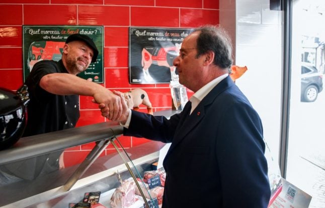Former French president, member of French left-wing Socialist Party (PS) and candidate for left-wing coalition Nouveau Front Populaire (NFP) in the Correze department Francois Hollande (R) shakes hands with a butcher as he meets locals during a campaign visit, ahead of the upcoming elections, in Ussel, central France