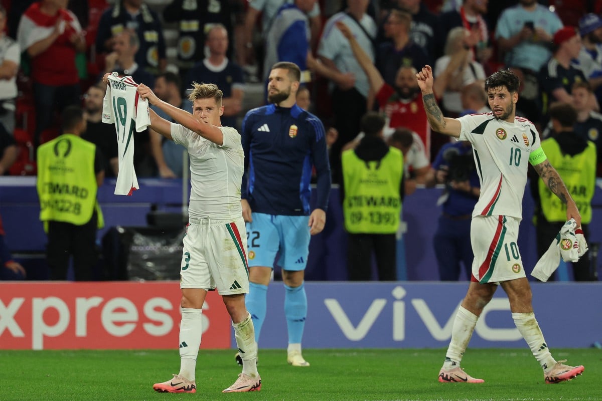 Hungary's forward Kevin Csoboth (L) celebrates scoring his team's goal while showing Hungary's forward #19 Barnabas Varga's jersey during the match between Scotland and Hungary at the Stuttgart Arena in Stuttgart on June 23, 2024. 