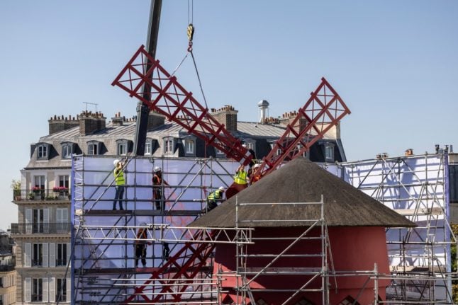 Workers install one of the four temporary windmill sails on the top of Paris's Moulin Rouge cabaret