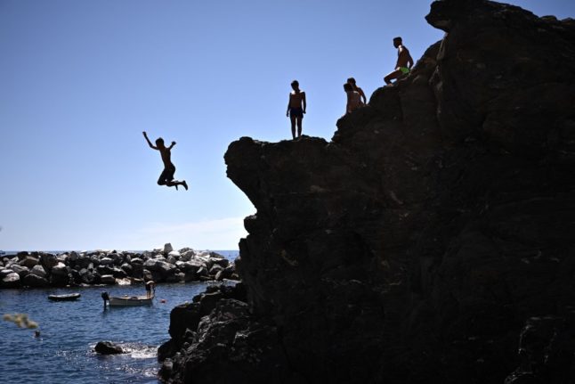 A youth dives into the sea from a cliff in Manarola, Liguria