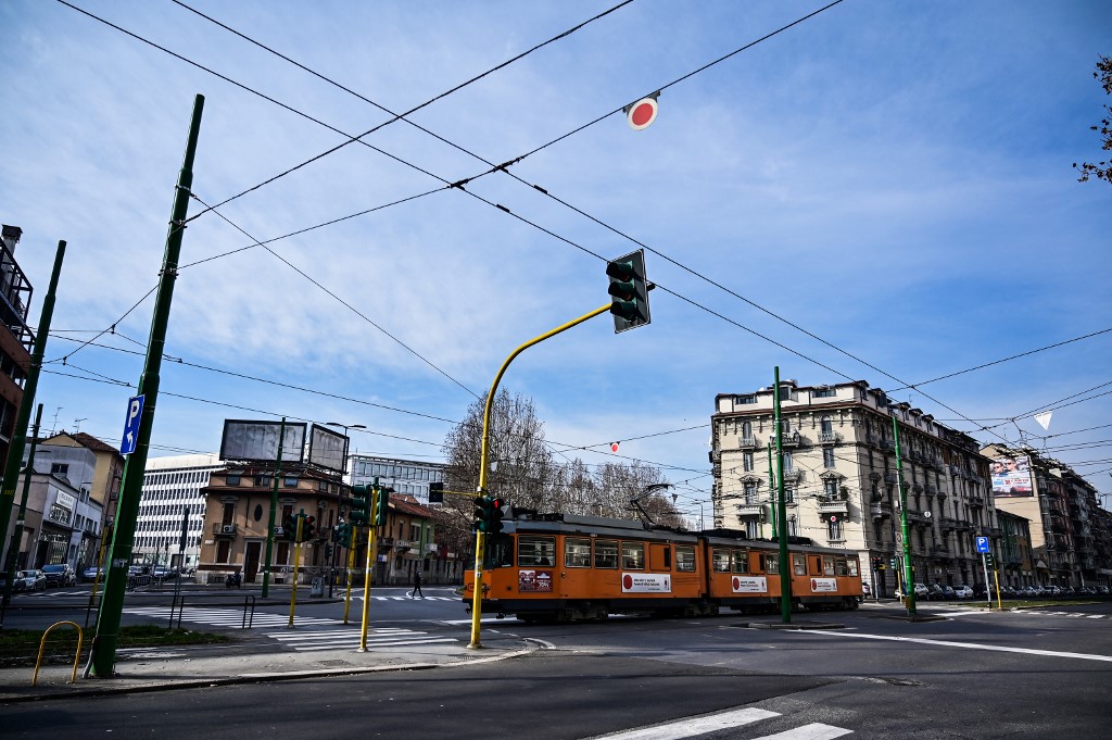 A tram rides past a junction in downtown Milan