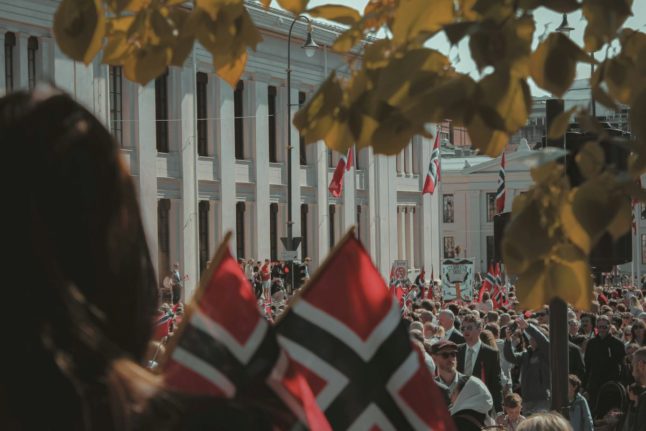 Pictured is a crowd of people with Norwegian flags.
