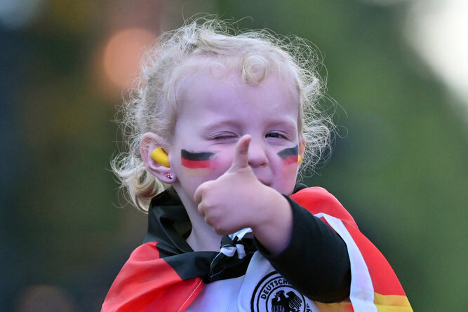A very young German football fan gives a thumbs up at the public football viewing area in front of Brandenburg Gate, in Berlin, Germany on June 14, 2024 ahead of the UEFA Euro 2024 opening football match between Germany and Scotland.