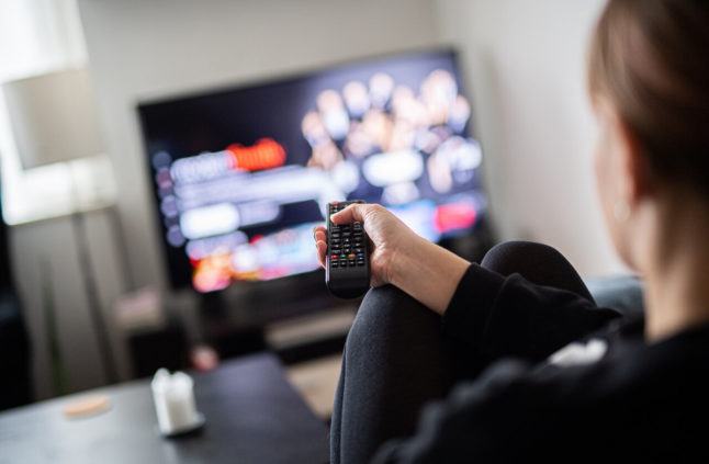 A person watches TV at home. Changes to cable TV connections in Germany are coming.