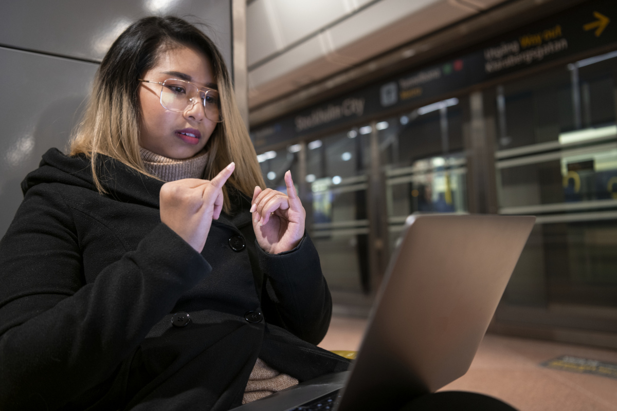 a woman talking in sign language in front of a laptop on the train