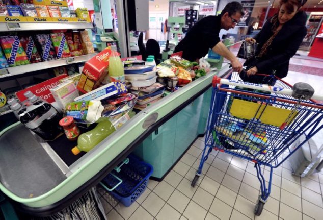 A woman empties her trolley at the till of a supermarket in Hazebrouck, northern France