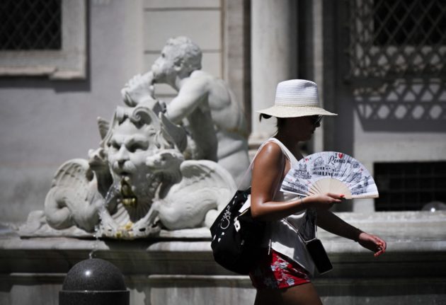 A woman waves a fan as she walks across Rome's Piazza Navona amid a heatwave.