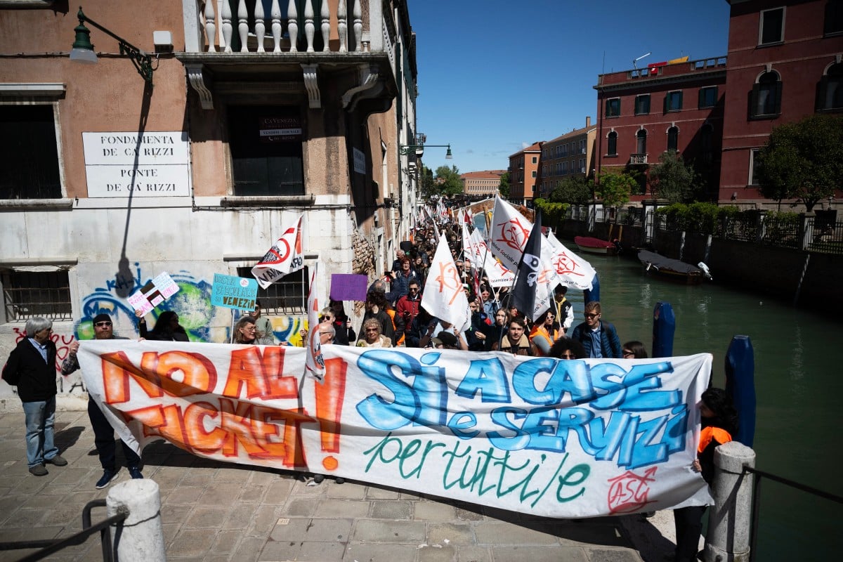 Protesters hold a banner reading 'No to the ticket, yes to houses and services for all' during a demonstration against Venice's entry fee scheme
