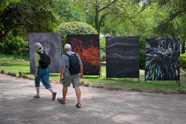 Visitors walk past photographs by French Marine Lanier on the opening day of Les Rencontres d'Arles photography festival