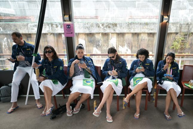 Members of the Brazilian delegation check their mobile phones ahead of the opening ceremony of the Paris 2024 Olympic Games