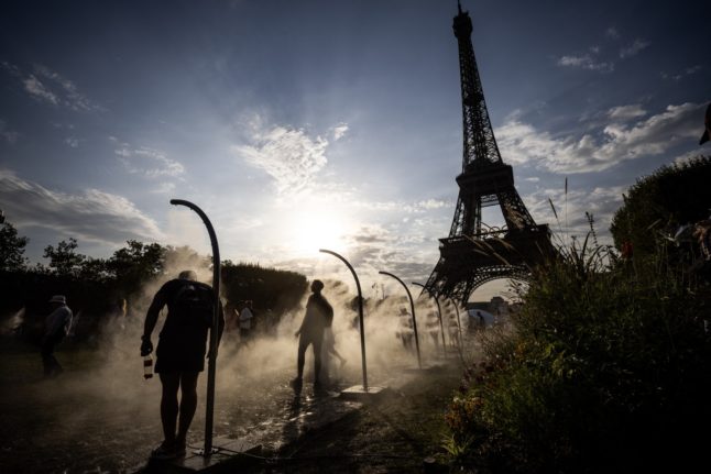 People cool off with water sprays beside the Eiffel Tower during the Paris 2024 Olympic Games