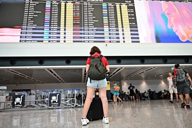 A passenger stands in front of a departure board at Rome's Fiumicino airport