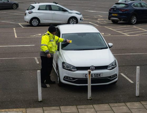 Pictured is a person issuing a parking ticket.