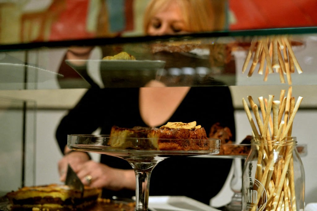 A woman cuts a piece of chocolate cake at a pastry shop in Rome