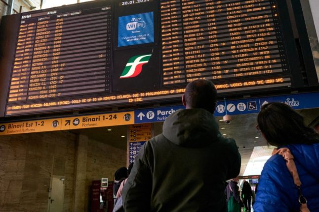 People look at a departure board at Rome's Termini railway station