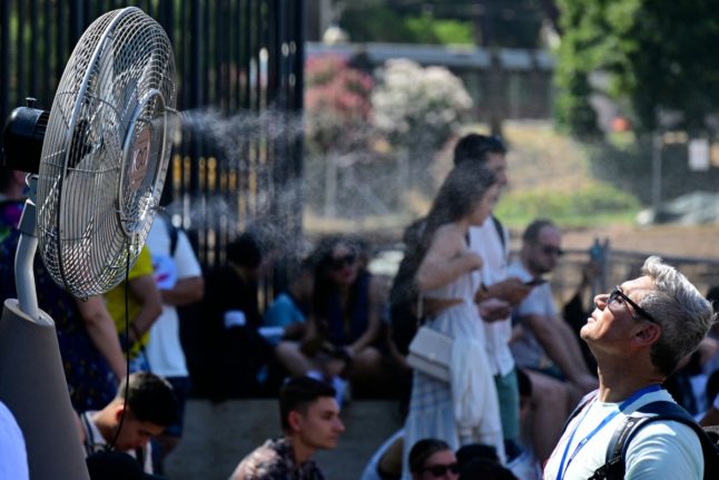 A fan sprays water in front of the gates of Rome's Colosseum to cool tourists