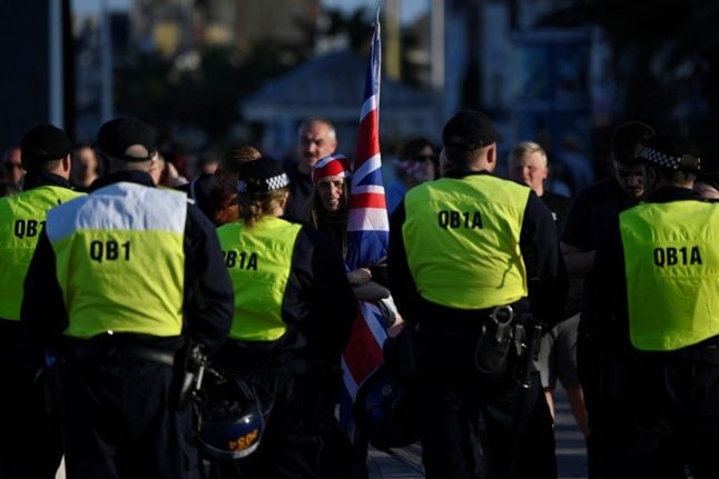 Police officers stand on duty opposite protesters of the 'Enough is Enough' demonstration called by far-right activists in Weymouth, on the southwest coast of England where the Bibby Stockholm migrant accommodation barge is moored, on August 4, 2024.