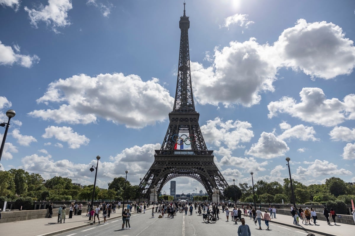 A French national flag flutters on the Eiffel Tower behind the Olympic rings following a ceremony commemorating the firemen who raised the French flag on the Eiffel Tower in 1944 after Paris was liberated from the Nazi occupation, in Paris