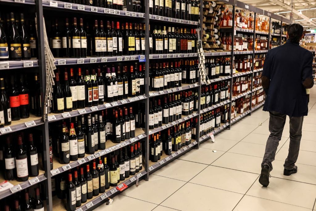 A customer walks past bottles of wine displayed in a supermarket