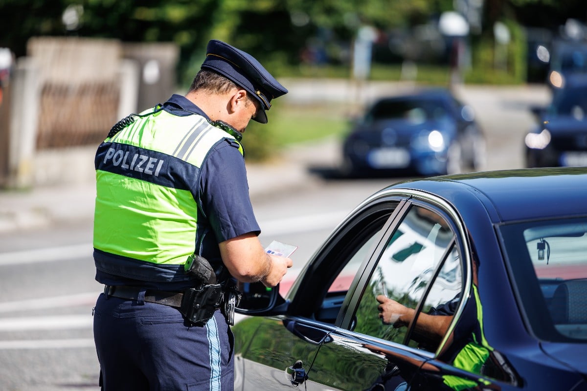 A police officer from the Bavarian border police checks a driver's documents at a checkpoint.