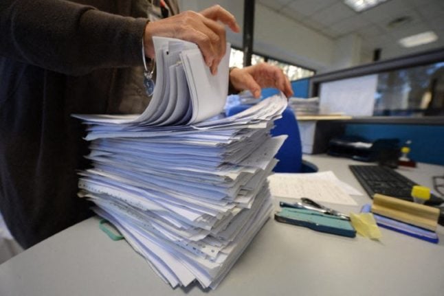 An Italian tax office employee goes through paper documents in an office