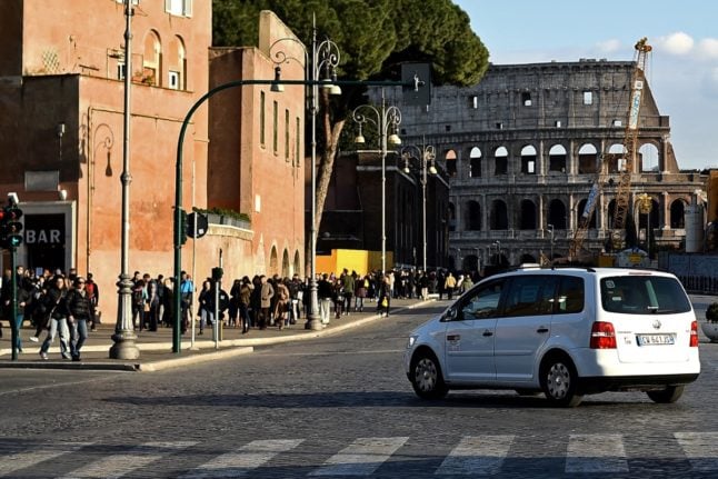 A taxi pictured in central Rome, with the ancient Colosseum in the background.