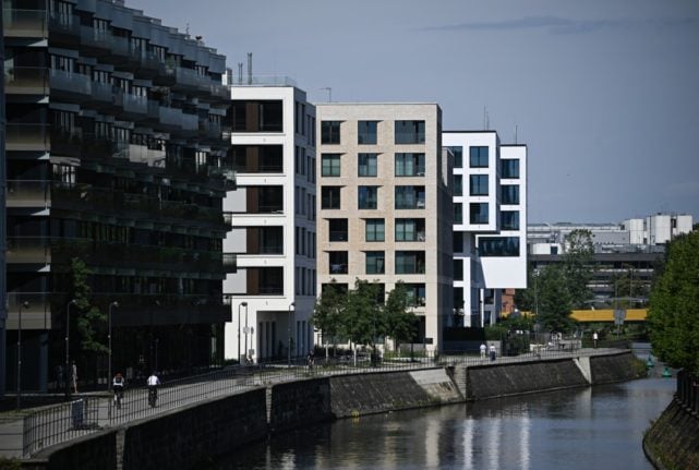 People walk past apartment buildings on the banks of the river Spree in the Heidestrasse quarter in Berlins Mitte (Centre) district