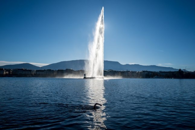 A lake-goer swims in an eight degree cold Geneva Lake at the 'Bains des Paquis' public bath downtown Geneva, with the Geneva's landmark fountain, known as 