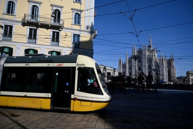 A public transport tram pictured in Milan, with the Duomo Cathedral in the background.