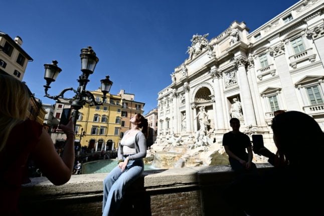 A tourist poses for a picture at the Trevi Fountain in 2024