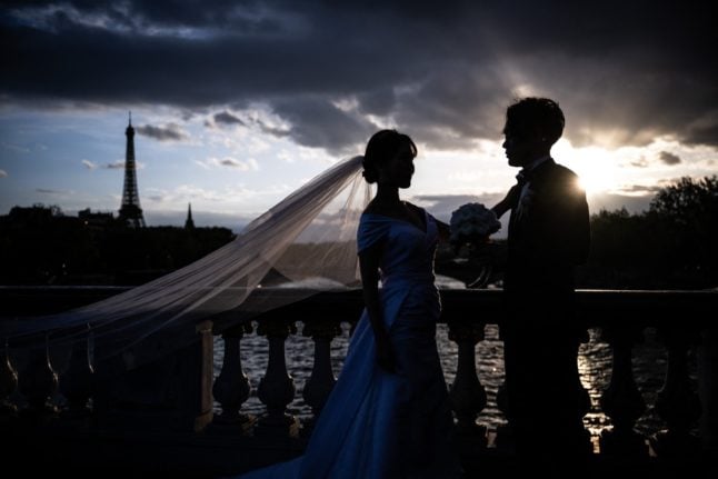 A newlywed couple pose at sunset on the Alexandre III bridge in Paris