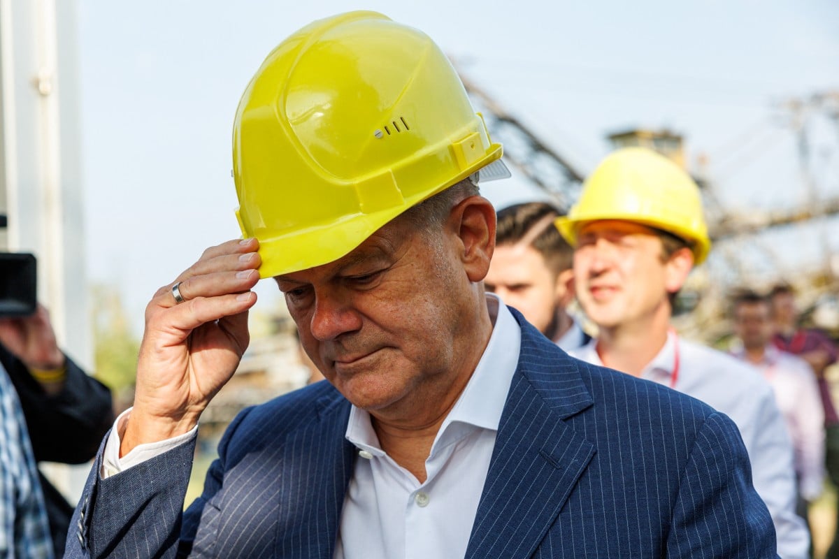 German Chancellor Olaf Scholz wears a helmet as he visits the Mining Technology Park and the recultivation of lignite mining in Grosspoesna near Leipzig, eastern Germany, August 30, 2024 ahead of regional elections. 