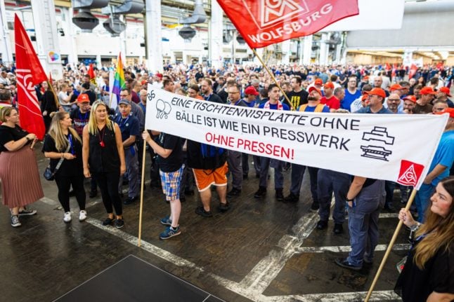 Employees of German car maker Volkswagen (VW) hold a banner reading 'A table tennis table without a ball is like a pressing plant without presses' as they stage a protest against the company's austerity plans in Wolfsburg, northern Germany