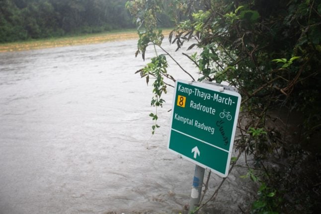 A cycle path signpost stands in the overflowed River Kamp near Altenhof, Austria