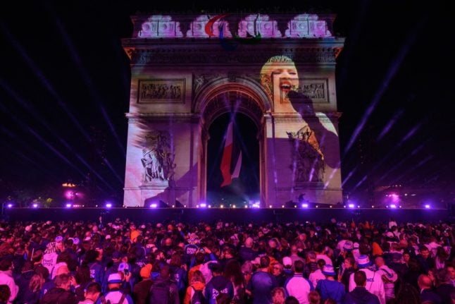 Attendees watch a recorded Lady Gaga performance projected on the Arc de Triomph at the end of the parade of French athletes who competed in the Paris 2024 Olympic and Paralympic Games in Paris