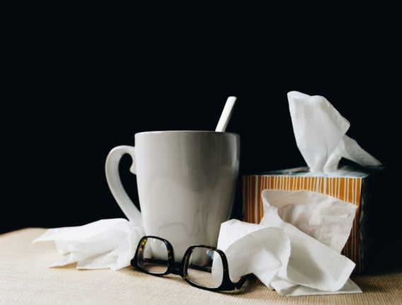 Pictured is a coffee cup next to tissues.