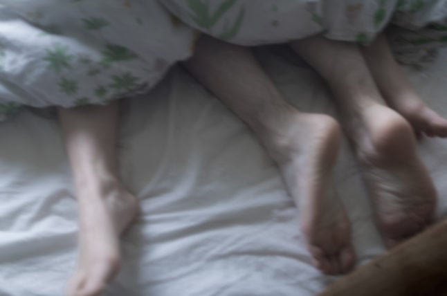 two pairs of feet underneath a duvet