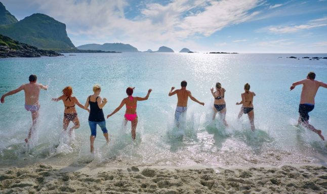 Pictured is a group of people running into the ocean.