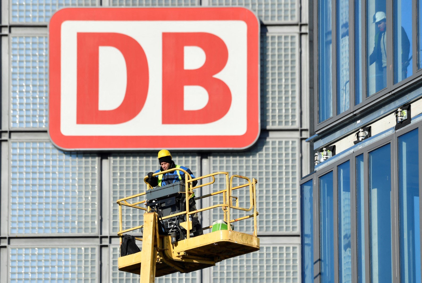 A worker operates a mobile lift in front of a giant logo of German rail giant Deutsche Bahn, at Berlin's central railway station (hauptbahnhof)