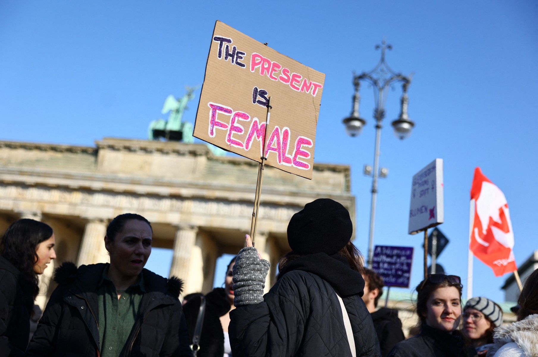 A protest sign reads 'the present is female' at womens day march in Berlin.
