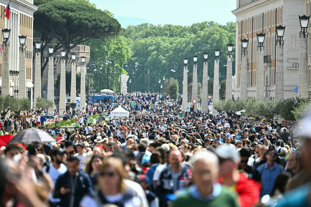 Faithful and pilgrims walk in Della Conciliazione street as they arrive to gather at St Peter's square following the death of Pope Francis in the Vatican 