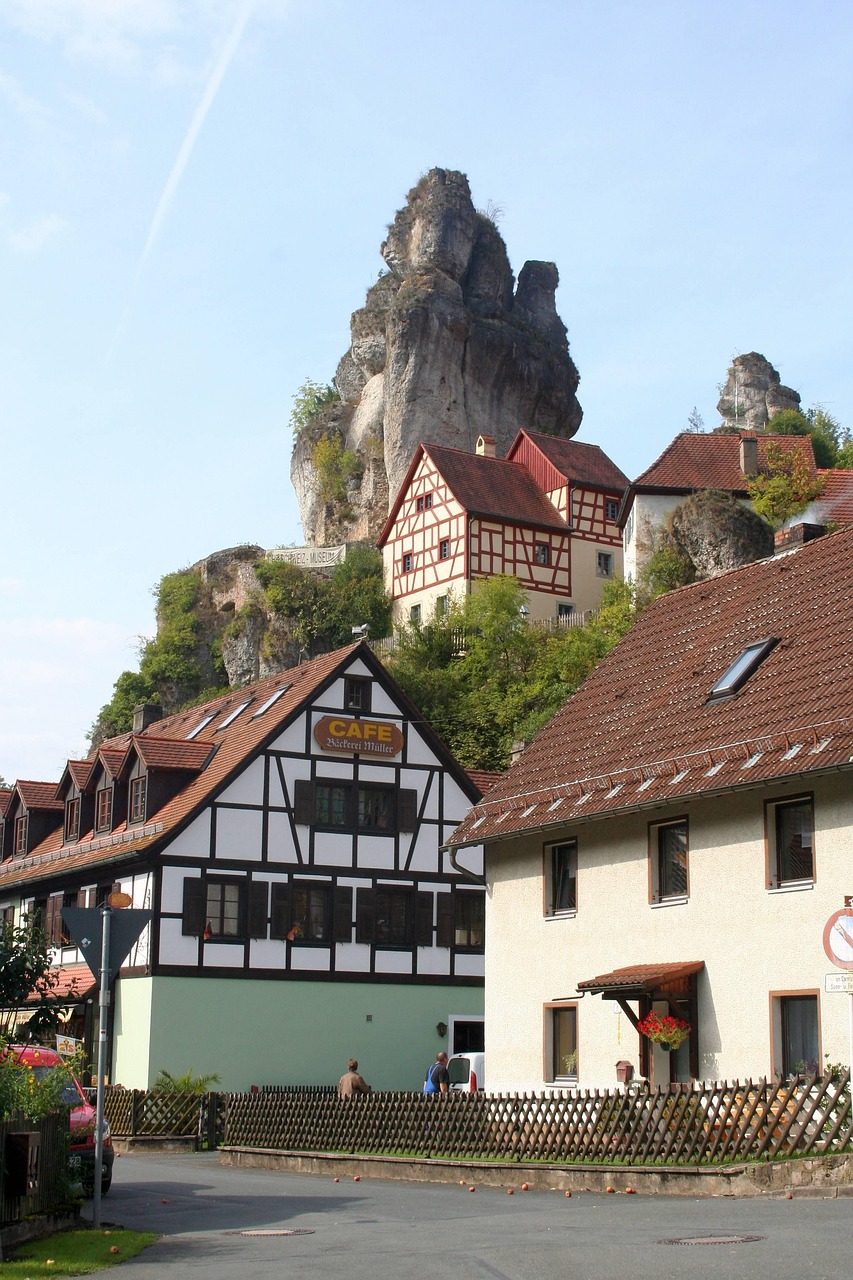 A rock spire rises about old German buildings in Pottenstien.